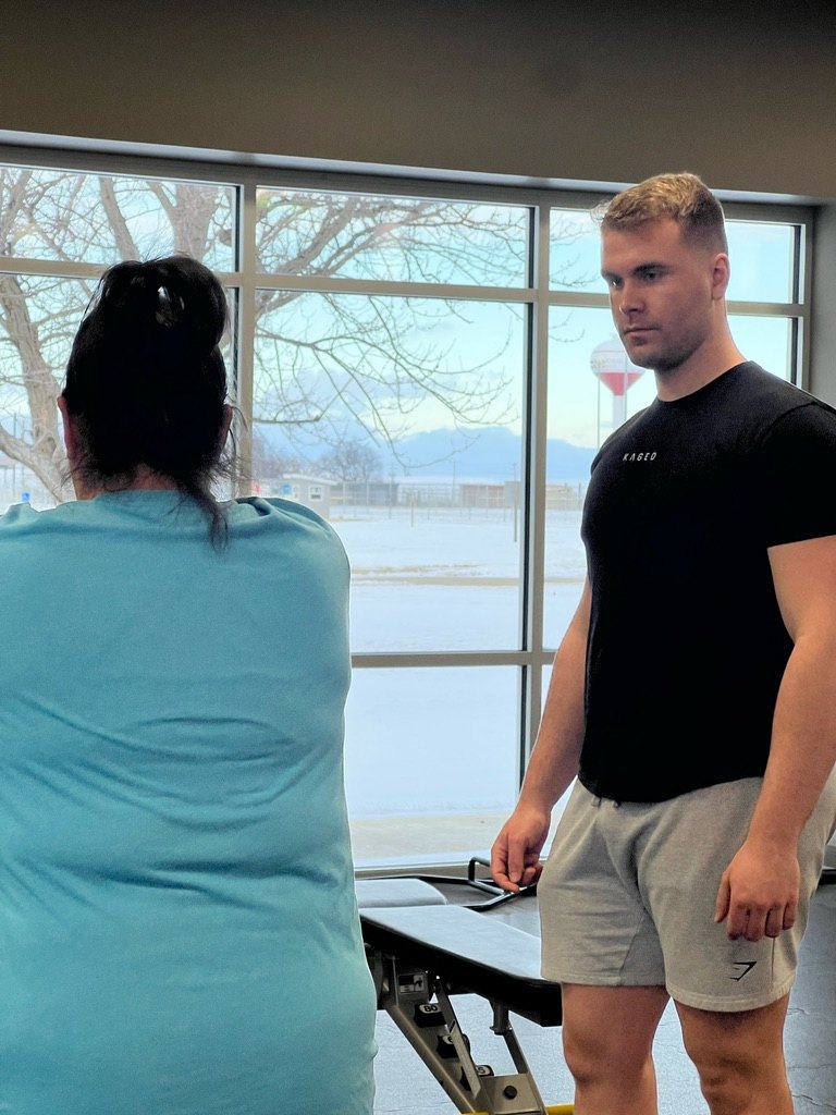 Tharin coaching a client through a training session at Buhler Wellness Center